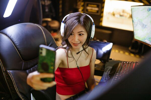 Gamer wearing headphones taking a selfie while seated at a gaming setup