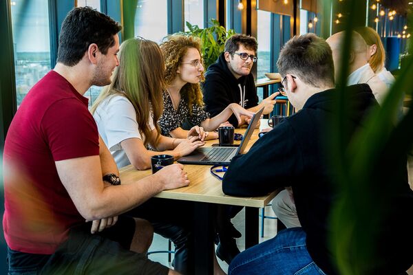 Keywords studios team sitting at a desk in the office for a meeting.
