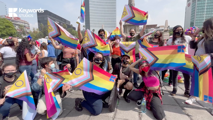 A group of employees from Keywords Studios posing together and holding Pride flags.